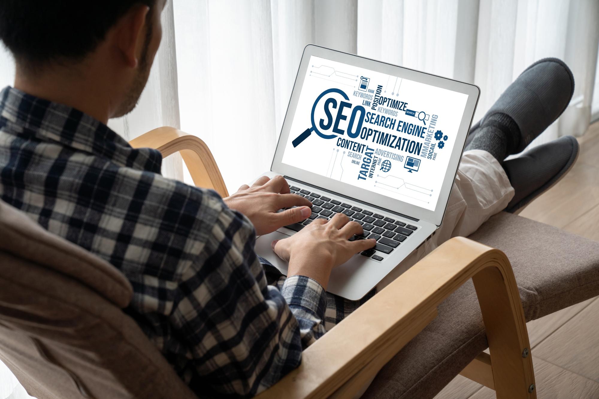 A person typing on a laptop, working on website content and optimizing for SEO to improve site rankings.